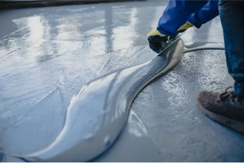 A photo of grey epoxy being spread on a driveway