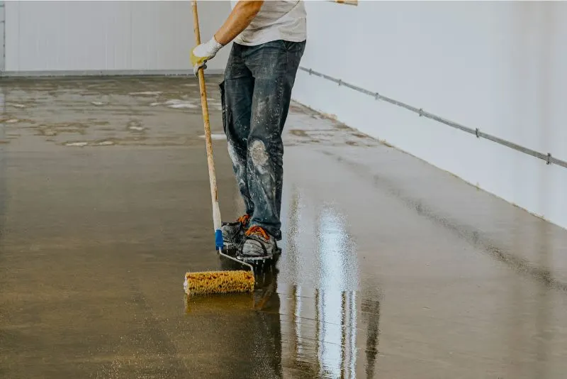 a man applying epoxy resin on a floor