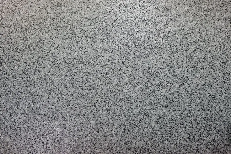 An exposed aggregate concrete with epoxy flooring over it