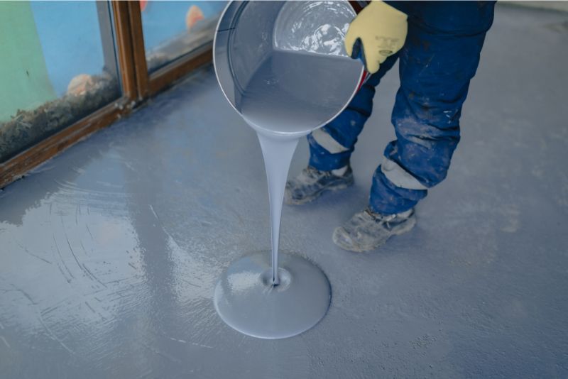 A photo of a man pouring epoxy resin on a surface